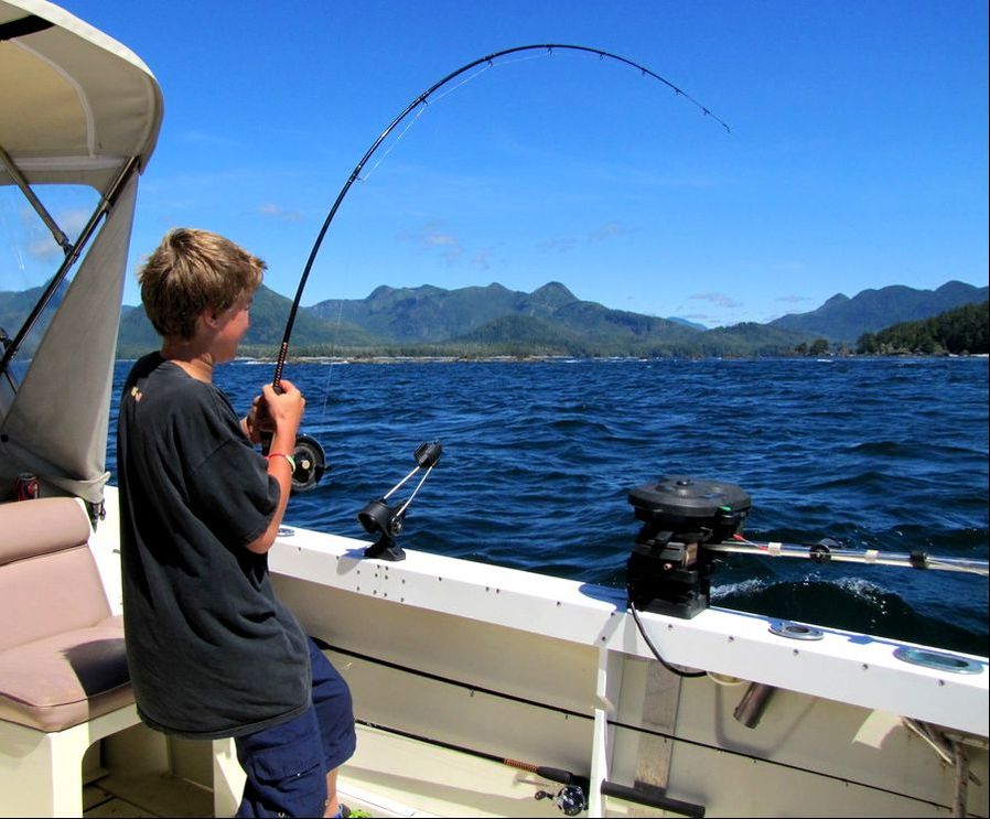 Boy fighting Salmon on fishing charter